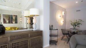 Ein modernes Wohnzimmer mit einer Holzkonsole, einer Couch, einem Esstisch mit Stühlen und Wandleuchten.