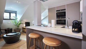 Eine moderne Küche mit einer großen Kochinsel, Barhocker, einem Einbauofen und einem Blumentopf.