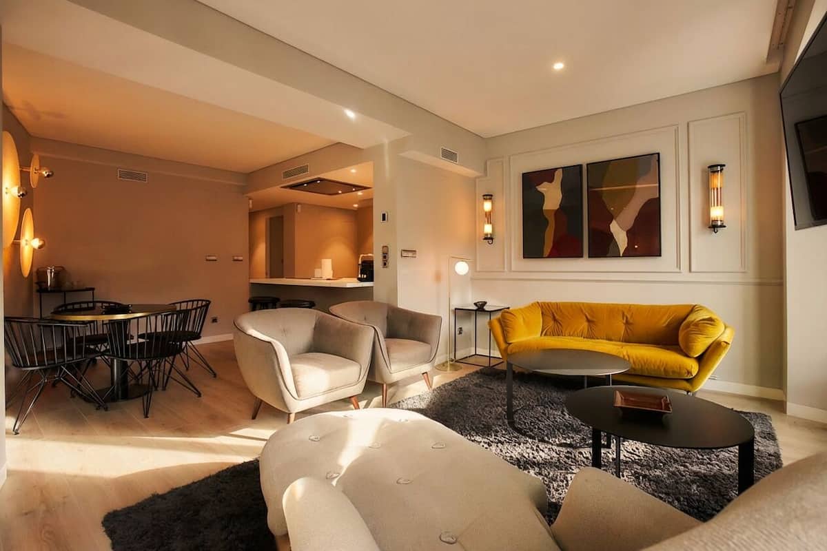 Una sala moderna con un sofá, sillones, una mesa de centro y un comedor con mesa y sillas.