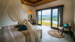 Quarto com cama de dossel, uma escrivaninha e vista para o exterior.