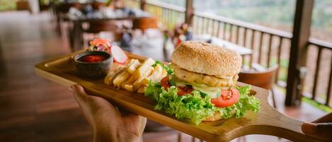 A wooden serving tray with a burger, fries, and a side salad.