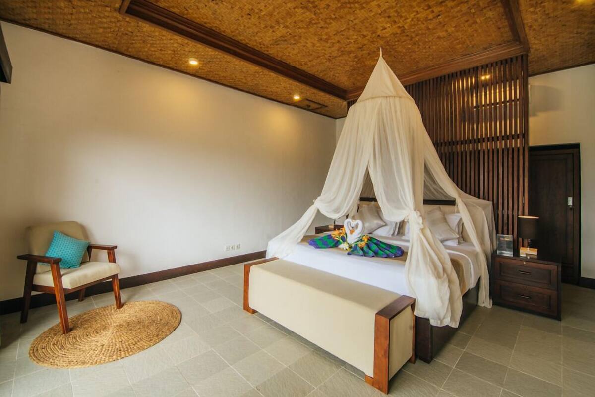 Une chambre à coucher avec un lit à baldaquin, une table de chevet, une chaise et un tapis tissé.