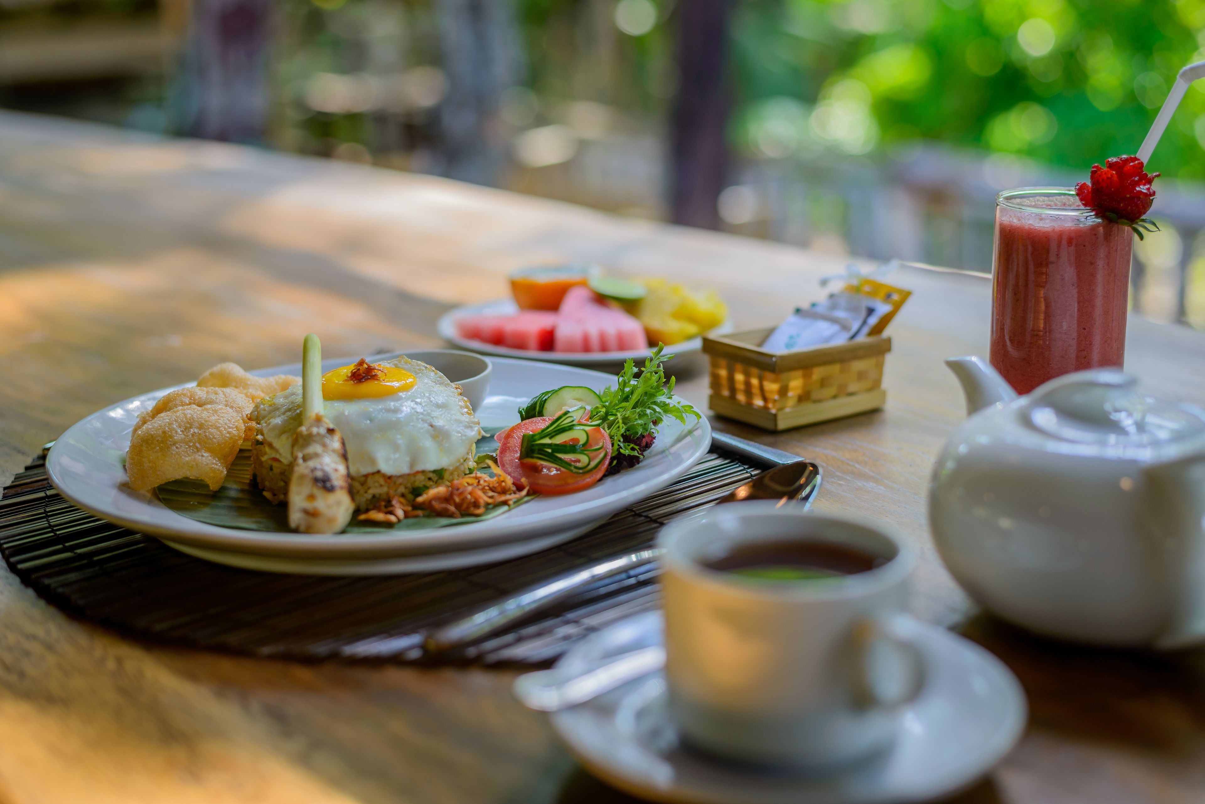 Ein gedeckter Tisch mit einer Mahlzeit, darunter ein Teller mit verschiedenen Speisen, eine Teetasse und ein Teekessel.