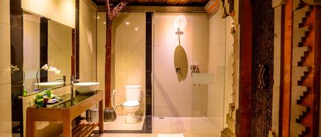 Un baño moderno con tocador de madera, un espejo grande, un lavamanos y un inodoro.