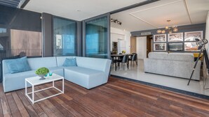 A modern living area with a light blue sofa, a white coffee table, and a dining area with a table and chairs. - Front of Beach -Luxurious Residence (Tel Aviv)
