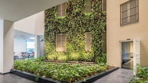 A modern interior with a vertical garden wall, a reception area, and a glass door entrance. - Front of Beach -Luxurious Residence (Tel Aviv)