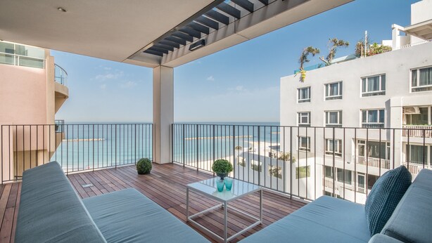A balcony with a wooden floor, a glass table, and a sofa. - Front of Beach -Luxurious Residence (Tel Aviv)