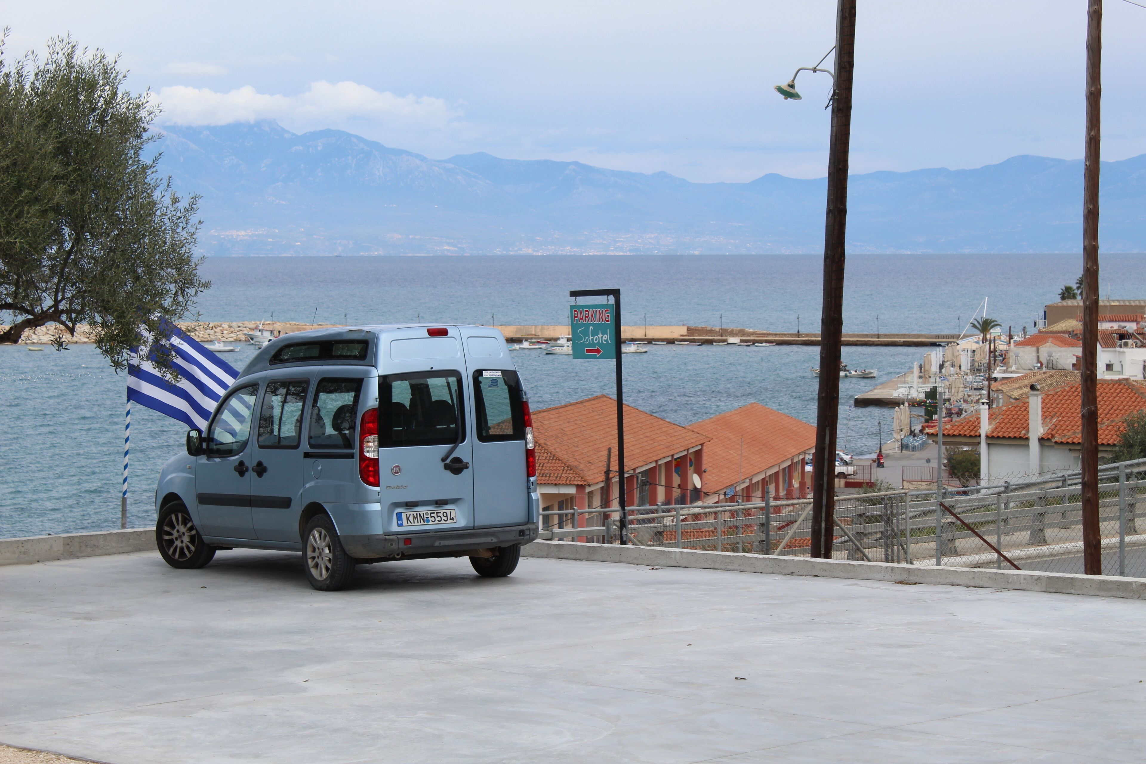 Una camioneta azul estacionada cerca de la costa, con un cartel que señala un área de estacionamiento.