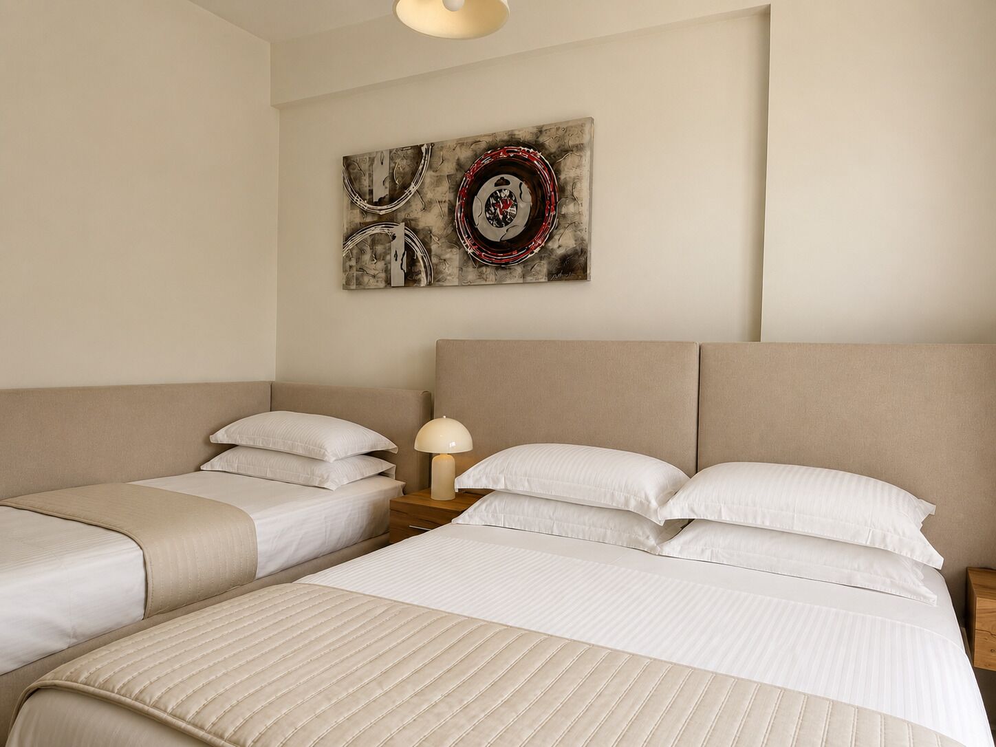 Ein Hotelzimmer mit zwei Betten, einem Nachttisch mit Lampe und einem Wandbild.