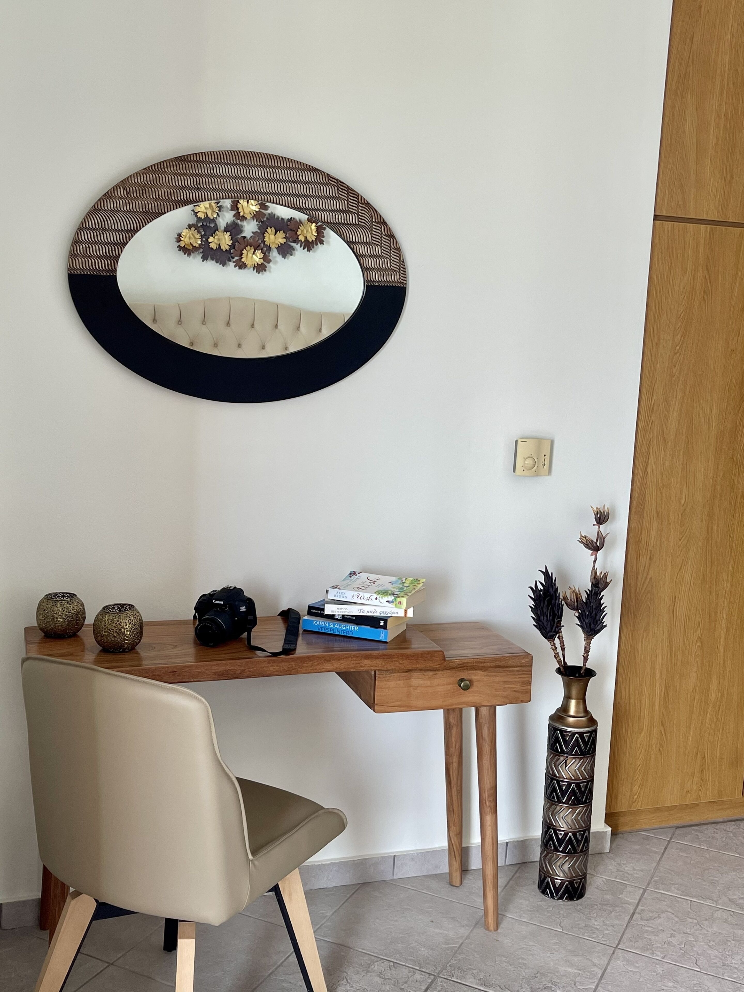 Een houten bureau met een camera, boeken en decoratieve objecten.