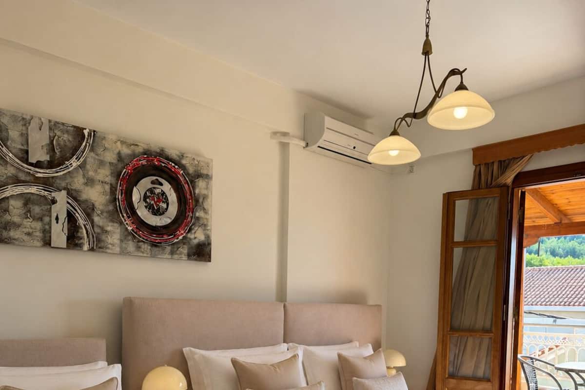 Quarto de hotel com duas camas, ventilador de teto, ar condicionado, uma obra de arte na parede e vista para o exterior.