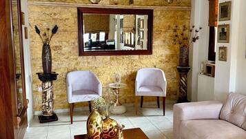 A living room with a stone wall, two white chairs, a wooden coffee table, and a beige sofa.