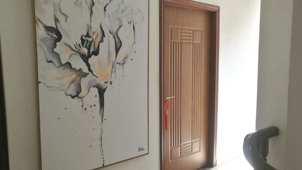 Un pasillo con un cuadro abstracto grande en la pared y una puerta de madera con diseño tradicional.