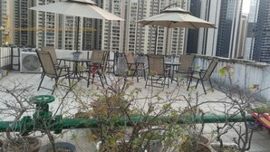 Una terraza en la azotea con mobiliario exterior y plantas en macetas.