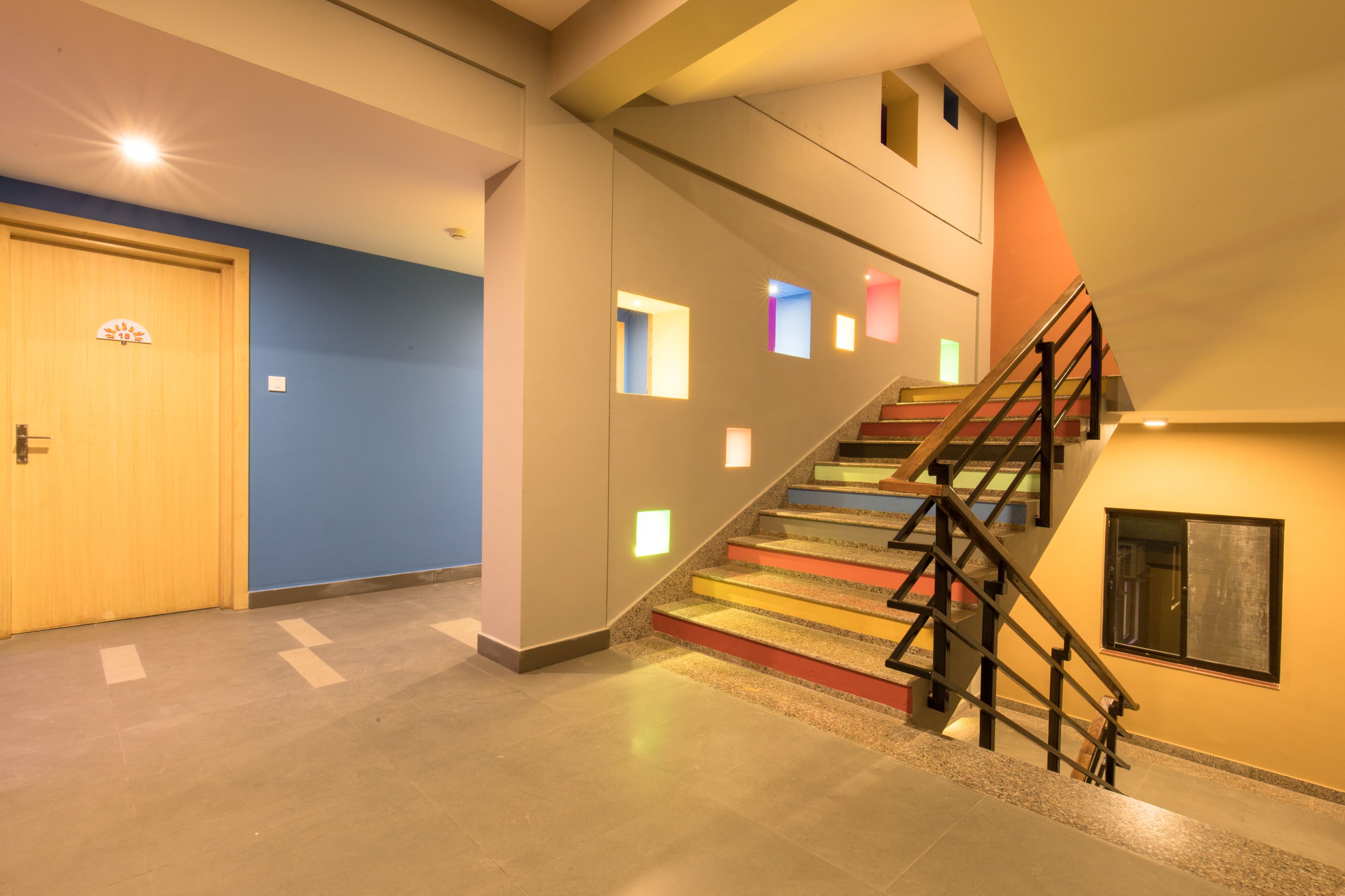 A modern interior with a staircase, a wooden door, and a blue wall.