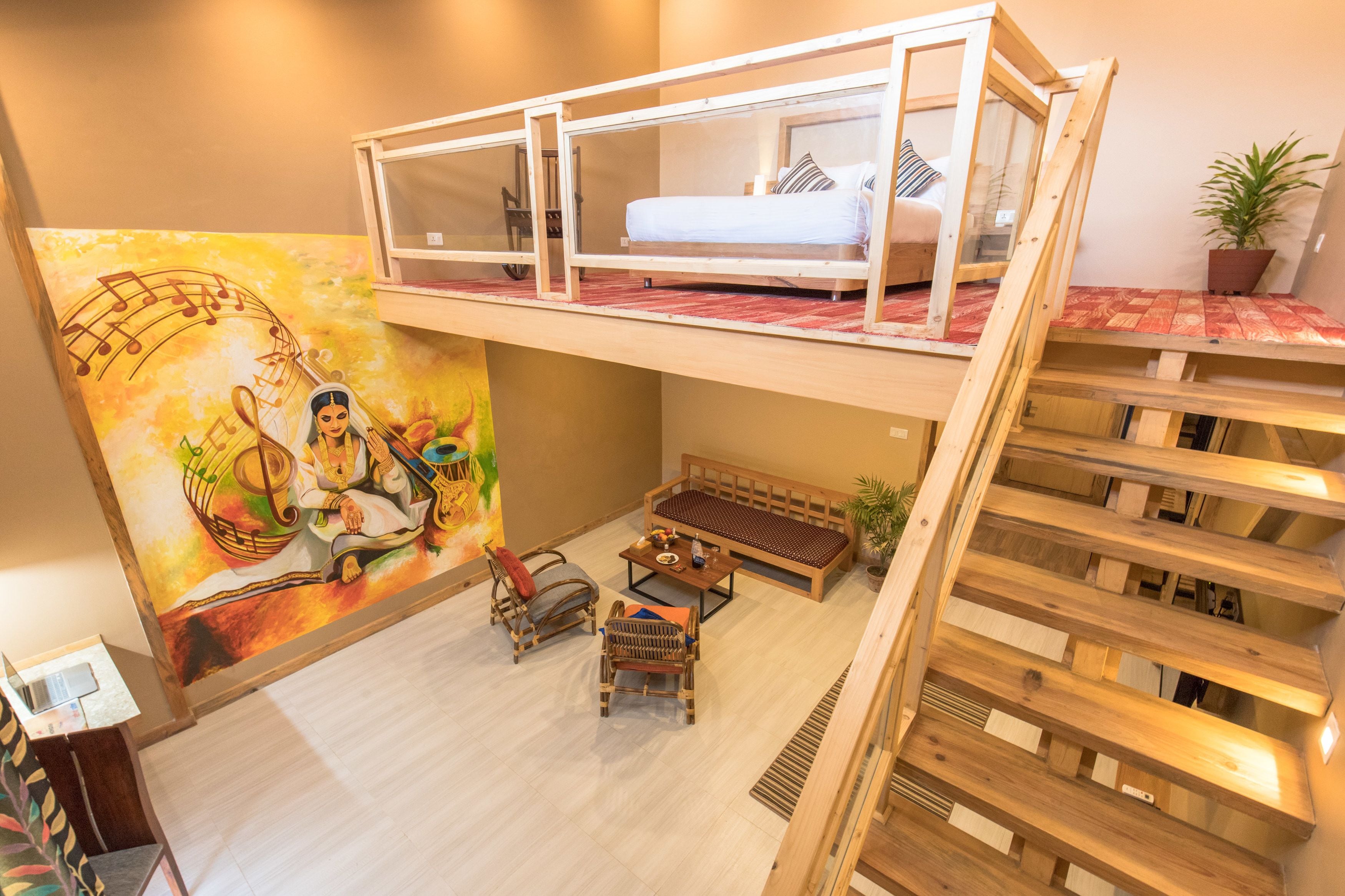 A multi-level room with a loft bed, a mural, a sofa, and a dining area.