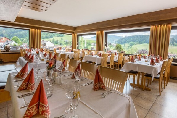 A restaurant with multiple tables set for dining, large windows offering scenic views, and a modern interior design. - BSW - Schwarzwaldhotel Baiersbronn (Baiersbronn)