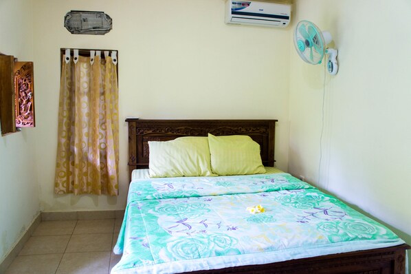 A bedroom with a bed, a curtain, an air conditioner, and a wall-mounted fan. - Shiva House Ubud (Ubud)
