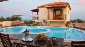 Zona de piscina con mesa lista para comer, sillas de descanso y vista a un edificio con balcón.