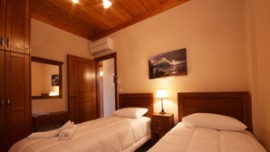 Habitación de hotel con dos camas individuales, cabeceros de madera, un cuadro en la pared y una mesita de noche con lámpara.