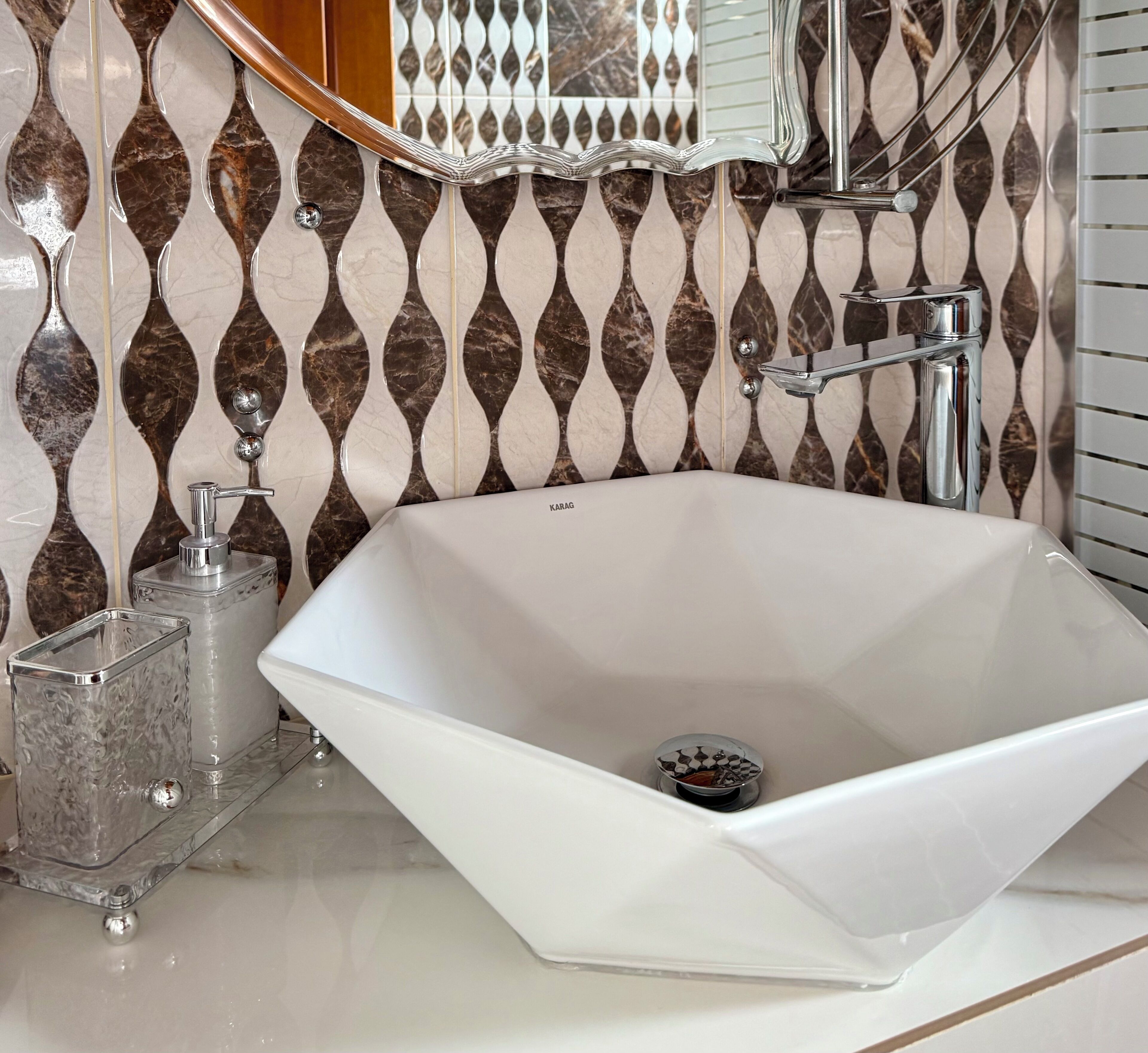 A modern bathroom with a freestanding bathtub, a glass soap dispenser, and a marble-patterned wall.