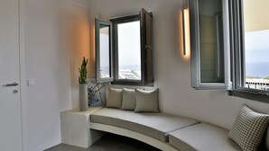 Une salle de bain moderne avec un banc intégré, une plante en pot et une vue sur la mer par les fenêtres.