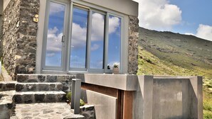 Un bâtiment moderne avec une façade en pierre, de grandes fenêtres et une vue sur une colline verdoyante.