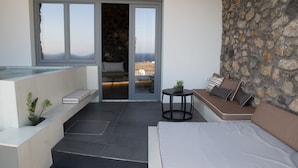 Un balcon avec un lit, une petite table et un coin salon agrémenté de coussins.