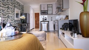 A modern kitchen with a built-in dishwasher, a coffee machine, and a TV. There is a large vase with flowers on the counter.