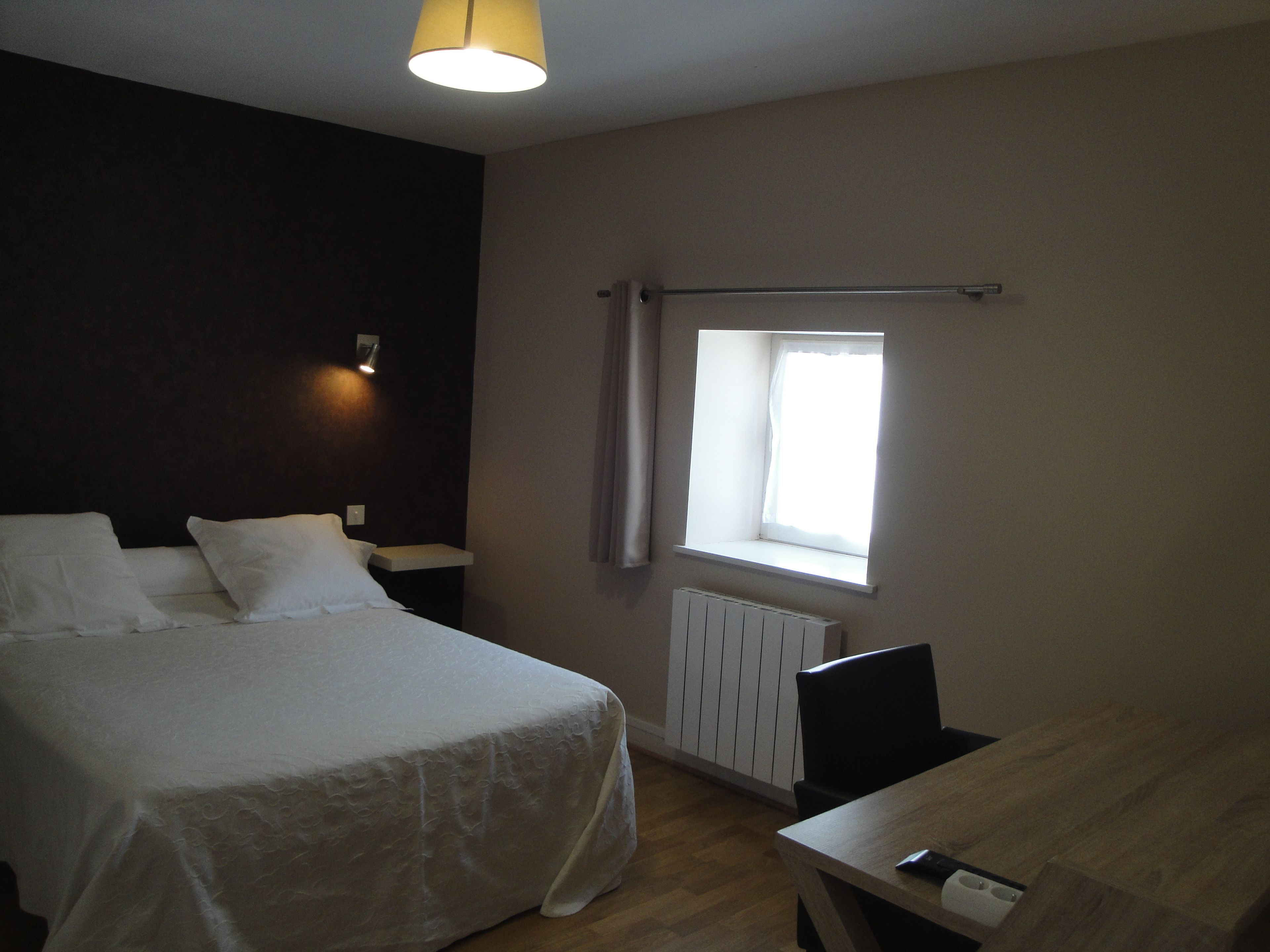 A bedroom with a bed, bedside table, lamp, window, and radiator.