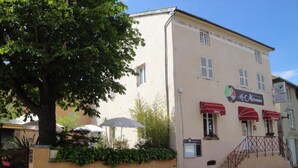 Kaksikerroksinen rakennus, jossa on kyltti, jossa lukee »Le Marronnier Hotel» ja »Restaurant». Sisäänkäyntiin johtaa portaikko, ja vasemmalla puolella näkyy puu.