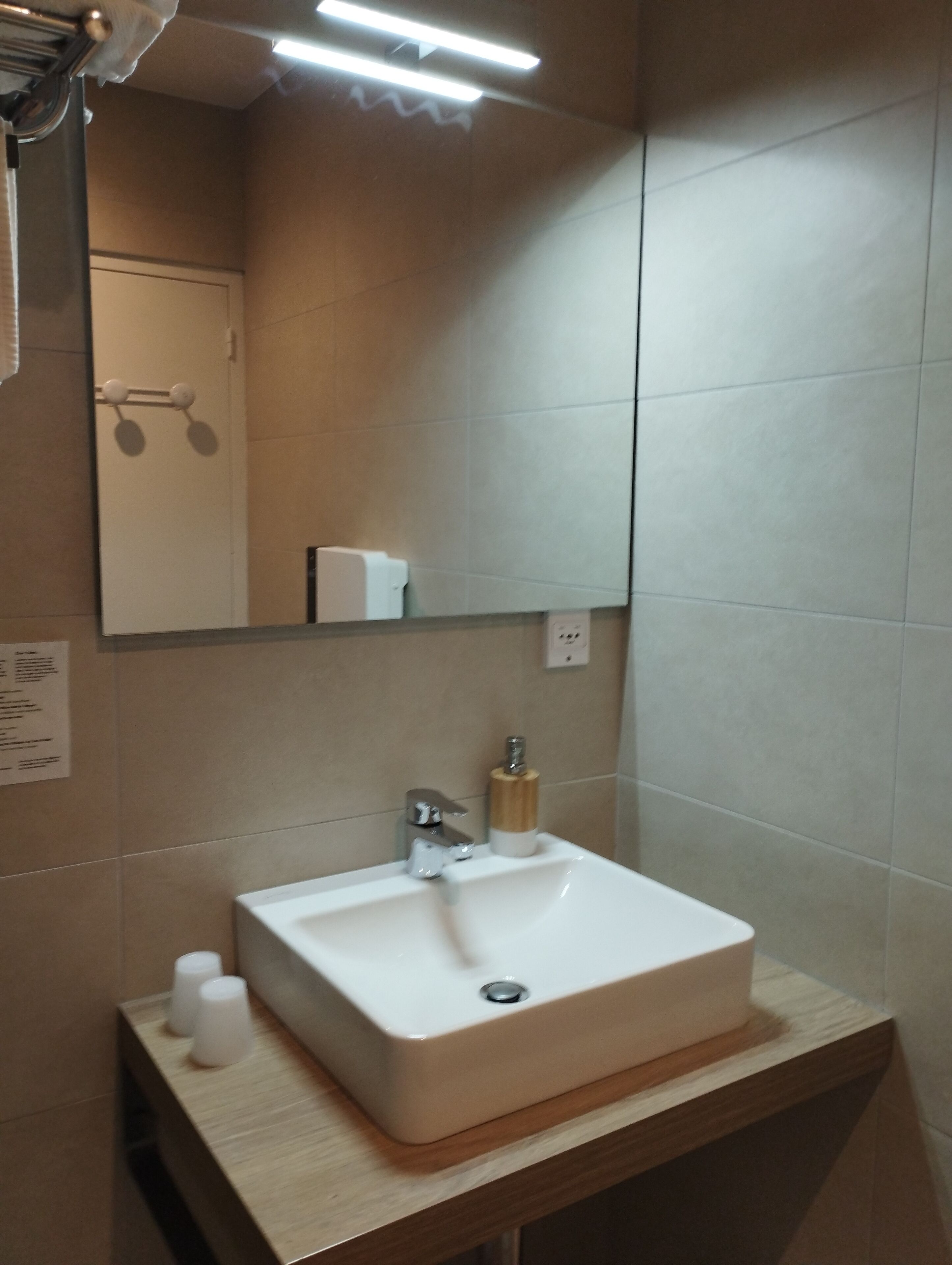 A bathroom with a white sink, a mirror, and a towel rack.