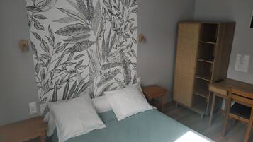 Un dormitorio con cama, armario y una mesita.