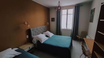 A hotel room with two beds, a desk, a chair, and a window with curtains.