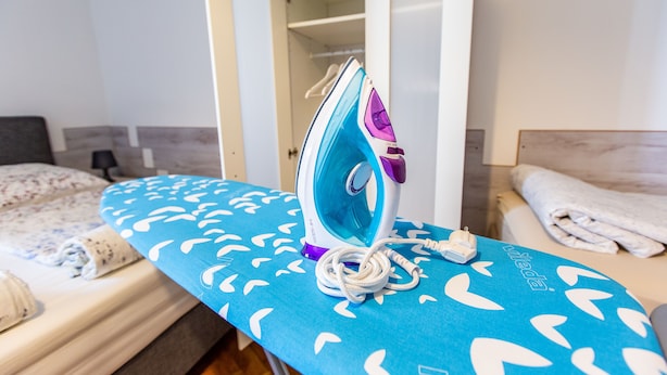 A neatly made bed with a blue ironing board and an iron in a hotel room. - Vienna Opera Appartment - free PARKING (Vienna)