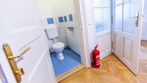A bathroom with a toilet, blue tiles, and a fire extinguisher. - Vienna Opera Appartment - free PARKING (Vienna)