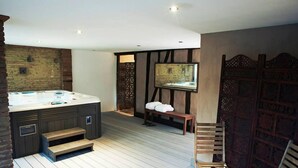 A modern bathroom with a large bathtub, wooden steps, a bench, and a small table with a teapot. - La Halte du Temps (Montesquieu-Volvestre)