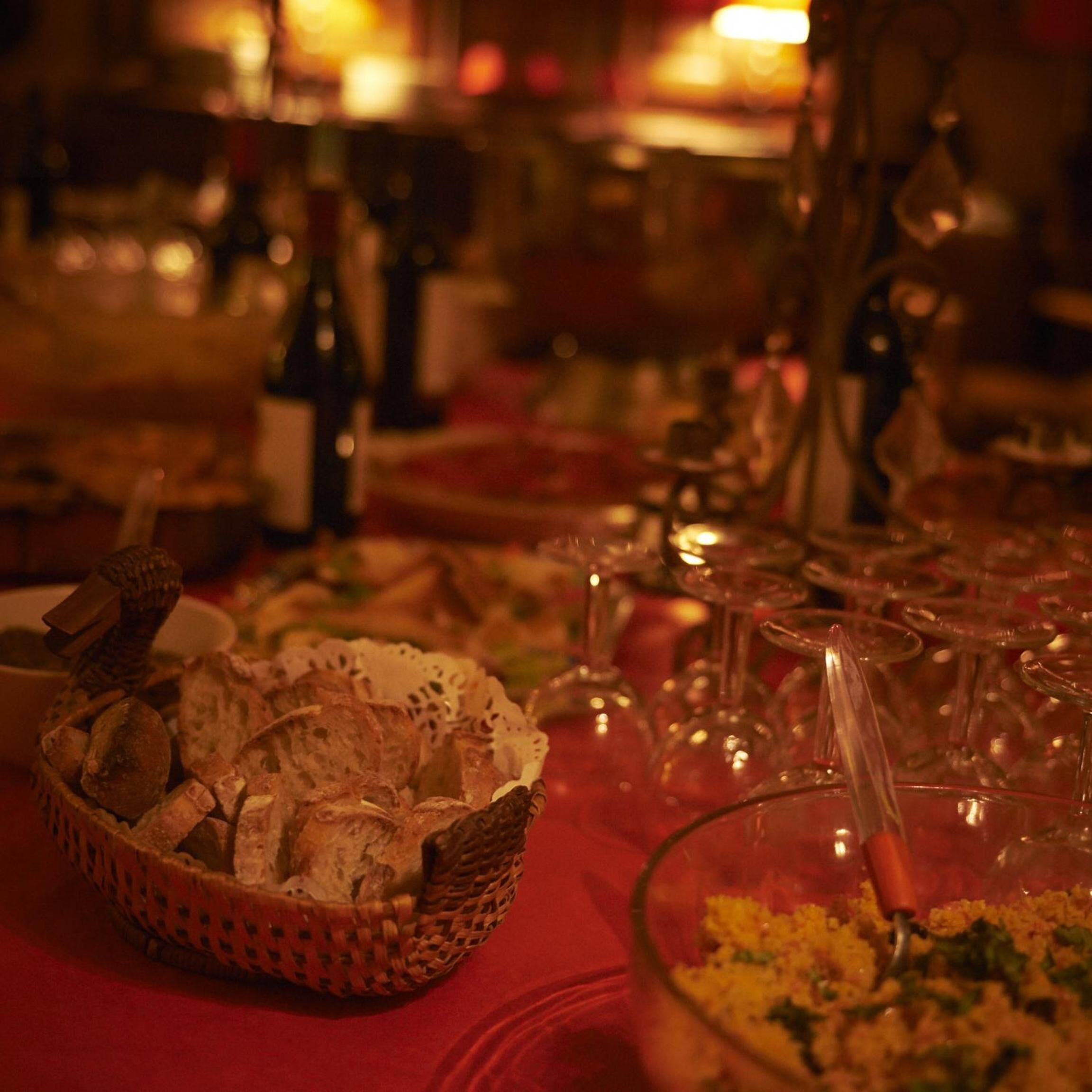 Una mesa de comedor con una cesta de pan, copas de vino y un bol de comida.