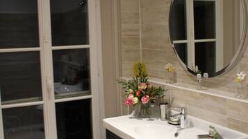 A bathroom with a large window, a sink with a mirror, and a small step leading to a shelf with toiletries.