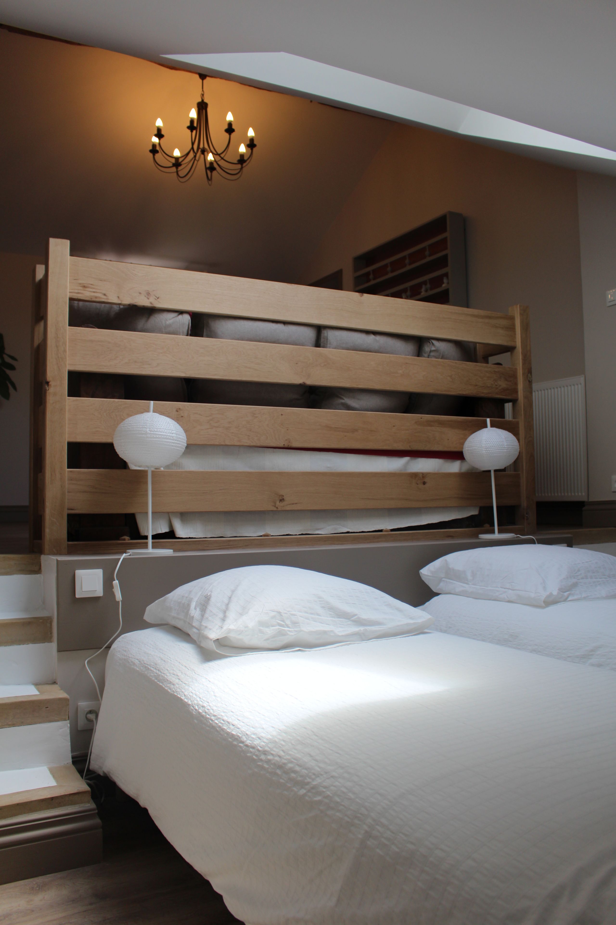 A bedroom with a wooden bunk bed, two bedside tables with lamps, and a chandelier.
