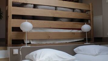 A bedroom with a wooden bunk bed, two bedside tables with lamps, and a chandelier.