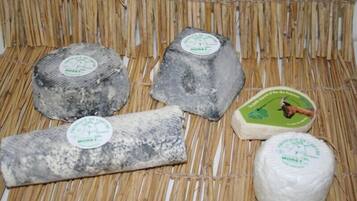 Four blocks of cheese with labels, placed on a woven mat.