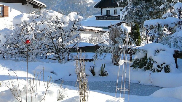 Eine verschneite Berglandschaft mit einem Chalet im Vordergrund.