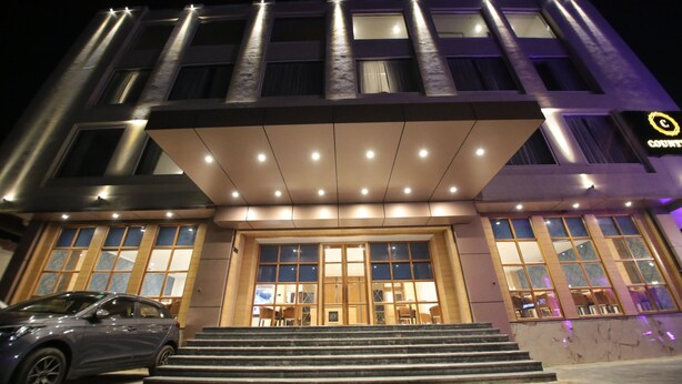 A modern hotel entrance with a car parked in front, large windows, and a well-lit facade. - County Inn Hotel (Jaipur)