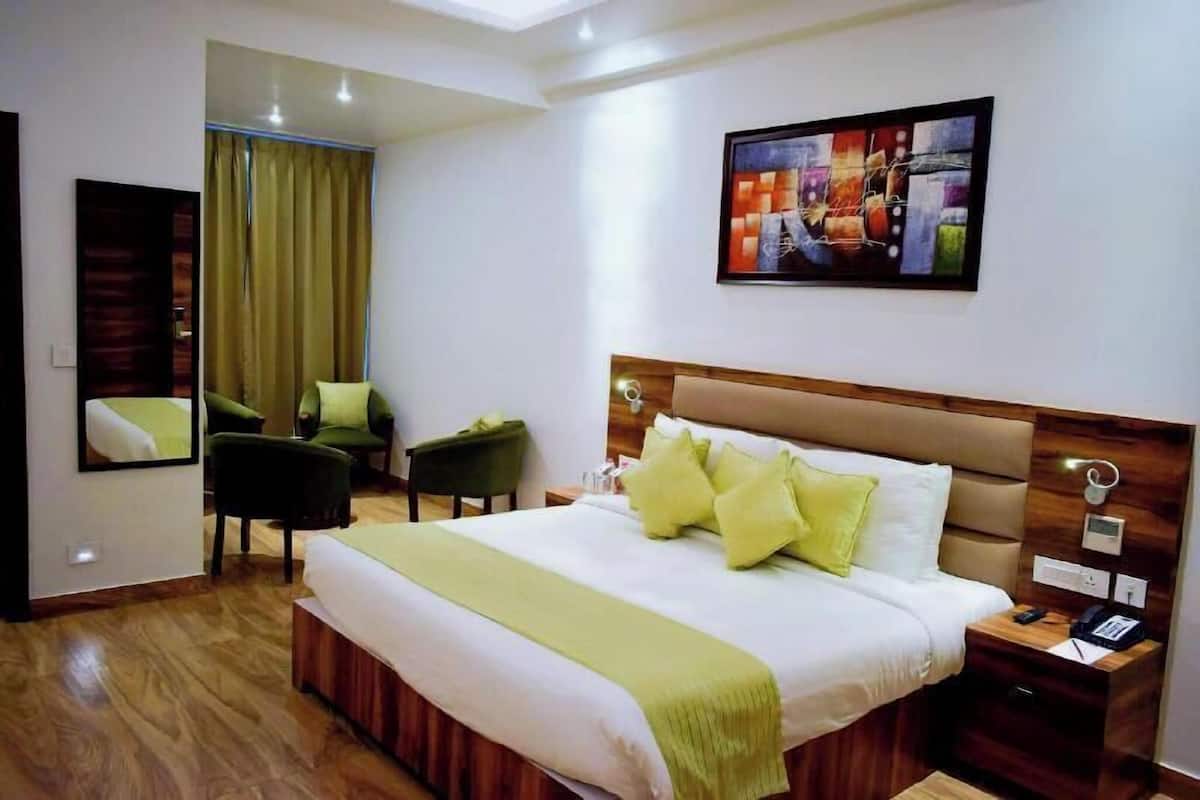 Una habitación de hotel con una cama, una mesita de noche, una silla y un cuadro en la pared.