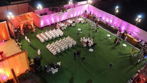An outdoor event space with a stage, seating, and tables arranged on a grassy area. - County Inn Hotel (Jaipur)