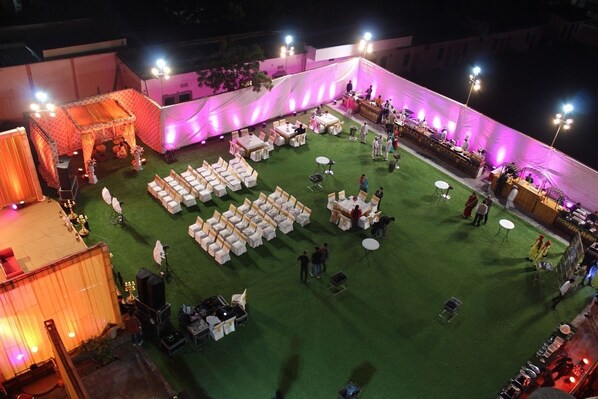 An outdoor event space with a stage, seating, and tables arranged on a grassy area.