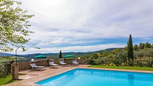 Una piscina rectangular amb un marc de maó i un cel blau clar al fons.
