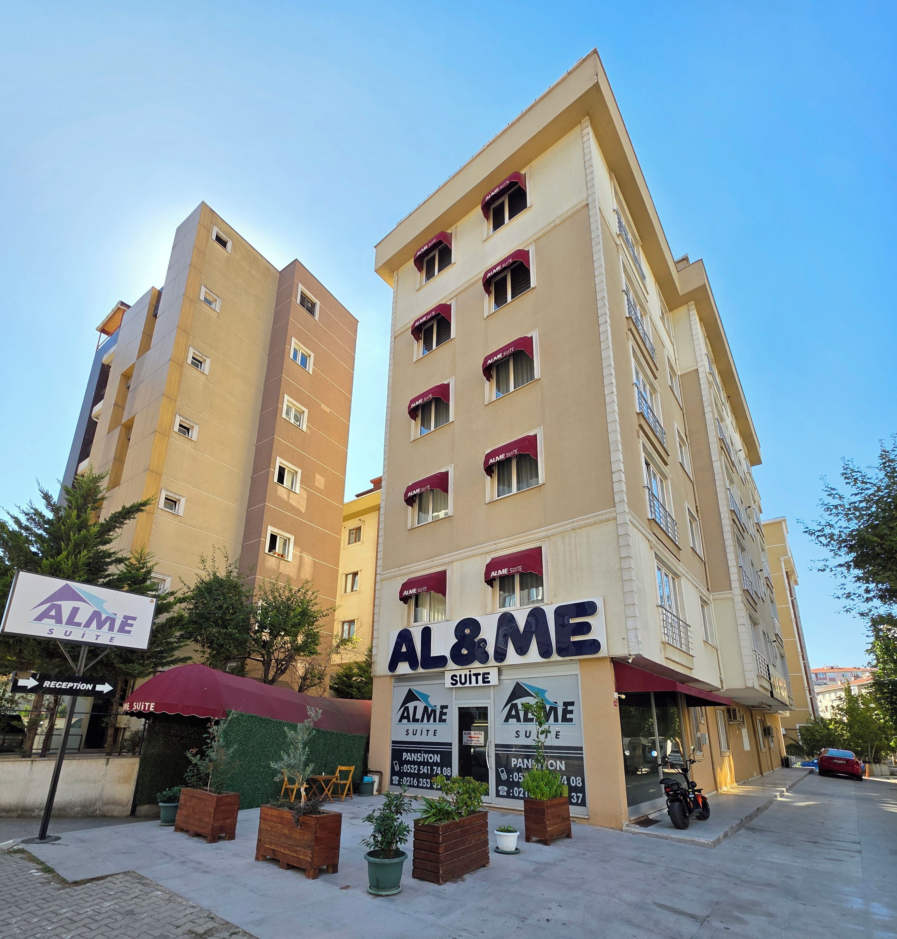 A hotel with multiple floors, a reception area, and outdoor seating with potted plants.