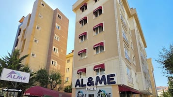 Un hotel con varios pisos, una zona de recepción y asientos exteriores con plantas en macetas.